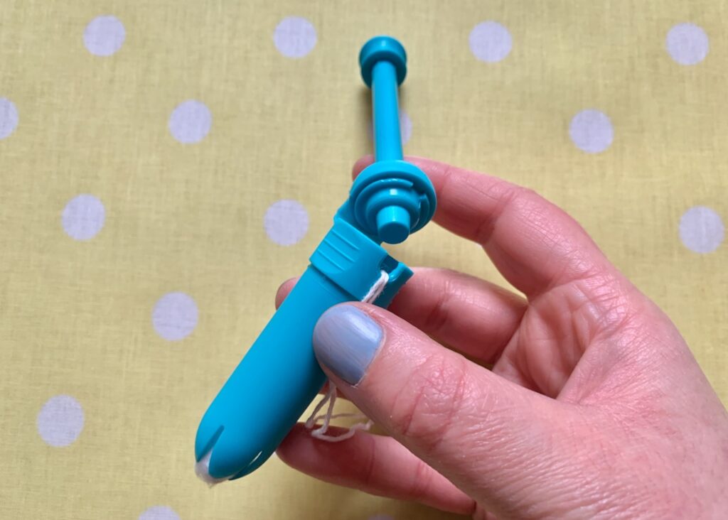 Holding a reusable tampon applicator with tampon contained and string hanging out.